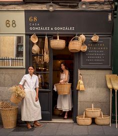 two people standing in front of a store with baskets on the door and one person holding a basket