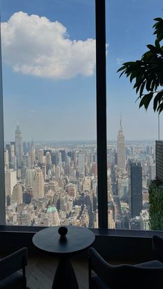 two chairs and a table in front of a large window overlooking the cityscape