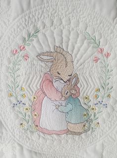 a white quilt with an image of a bunny hugging a rabbit