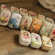 there are many small tins that have flowers on them, all lined up together