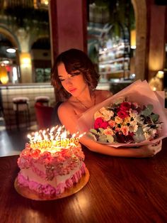 a woman sitting in front of a cake with candles on it