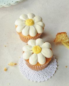 two cupcakes with white frosting and yellow centers