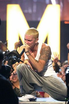 a man sitting on top of a stage holding a microphone in front of a crowd