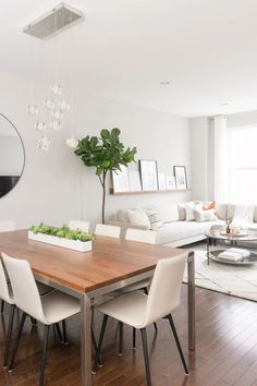 a dining room table with chairs and a mirror on the wall above it in front of a couch