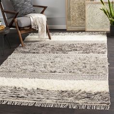 an area rug with fringes on it in a living room next to a chair