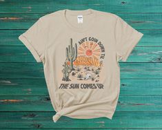 Get ready to rock the summer with our Desert Western Summer T-Shirt. This vintage-inspired tee features a bold graphic print of a desert landscape, complete with a classic Western font. Crafted from high-quality, soft materials, this tee is designed for both comfort and durability. The classic fit and unisex design make it a versatile addition to any wardrobe. The vintage-inspired graphic and muted colors give it a unique, retro feel, perfect for both casual and dressy occasions. Whether you're hitting the beach or just lounging at home, this Desert Western Summer T-Shirt is the perfect choice for summertime fun. The breathable fabric is perfect for warmer weather, and the high-quality construction ensures that it will hold up to wear and tear over time. This vintage Summer Graphic T-Shirt Summer Adventure T-shirt With Text Print, Relaxed Fit T-shirt For Summer Adventure, Summer Adventure Graphic Print T-shirt, Retro Outdoor Graphic Print T-shirt, Summer Outdoor T-shirt With Front Print, Retro Graphic Print T-shirt For Outdoor, Vintage Adventure Graphic T-shirt, Vintage Graphic Print T-shirt For Adventure, Vintage Summer Outdoor T-shirt