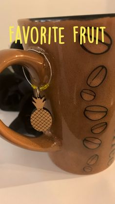 a coffee mug with a pineapple keychain hanging from it's side