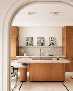 an open kitchen with marble counter tops and wooden cabinetry, along with stools