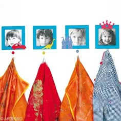 four pictures hang on the wall with clothes hanging in front of them and two children's faces