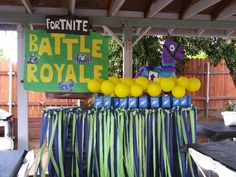 the table is set up with yellow balloons and blue bags for battle royale party decorations