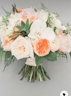 a bridal bouquet with peach and white flowers on a gray background for a wedding