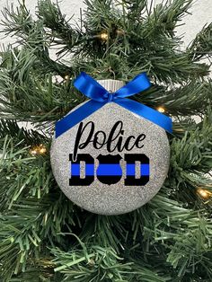 a police ornament hanging on a christmas tree with blue ribbon and lights around it