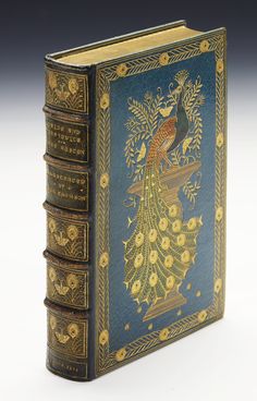 an antique book with gold trimming and blue cover, featuring a peacock on it