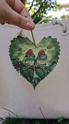 someone holding onto a heart shaped bag with two frogs on it