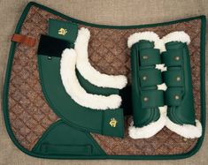 a green and white horse saddle with two boots on the side, sitting on top of it