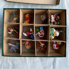 an open cardboard box filled with disney figurines on top of a white table