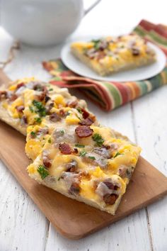 two slices of pizza sitting on top of a wooden cutting board next to a cup