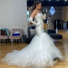 a woman in a wedding dress is taking a selfie with her cell phone while standing on a wooden floor