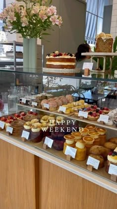 a display case filled with lots of different types of cakes and pastries on top of wooden shelves