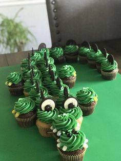 cupcakes with green frosting and googly eyes are arranged in the shape of a caterpillar