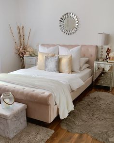 a bedroom with a bed, nightstands and mirror on the wall above it's headboard