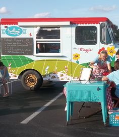 some people are sitting at a table in front of a food truck