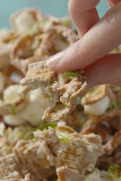 a hand picking up some food from a bowl