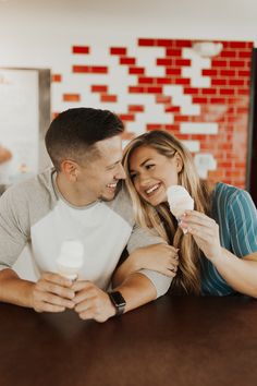 a man and woman sitting at a table eating ice cream