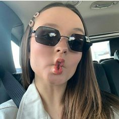 a woman sticking her tongue out in the back seat of a car while wearing sunglasses