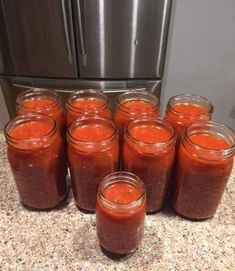 several jars filled with red liquid sitting on top of a counter