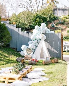 a teepee tent is set up in the yard with balloons and pillows on it