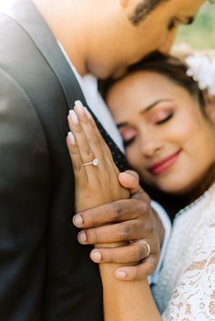 a bride and groom embracing each other with their wedding rings on their fingers in front of them