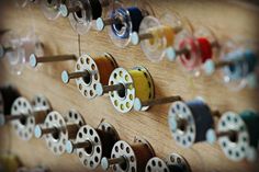 many spools of thread are hanging on a wooden board with holes in it