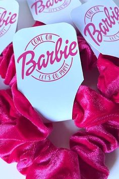 some pink scrunffles that are on top of a white table and one has the word barbie on it