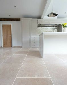 an empty kitchen with white cabinets and tile flooring in the middle of the room