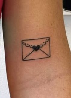 a small envelope tattoo on the left side of the arm with a heart in it