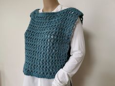 a mannequin wearing a crocheted blue vest and white shirt with buttons