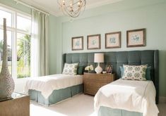 two beds in a bedroom with green walls and white bedding, framed pictures on the wall