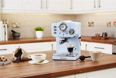 an espresso machine sitting on top of a kitchen counter next to a cup of coffee