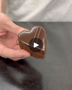 a person holding a heart shaped chocolate cookie