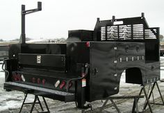 a black grill sitting on top of a metal stand in front of snow covered ground