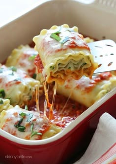 a casserole dish filled with lasagna and cheese being lifted from the casserole