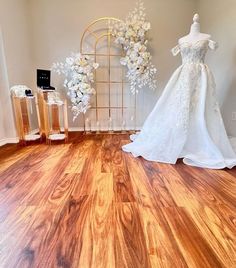 a wedding dress and bouquet on display in a room with wood flooring at the bottom