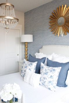 a bedroom with blue and white bedding, chandelier and flowers