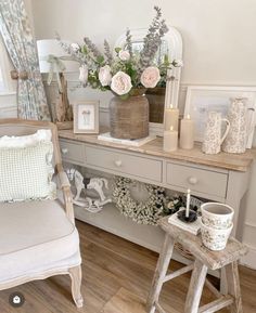 a white chair sitting next to a table with flowers on it and candles in vases