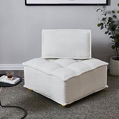 a white chair sitting on top of a carpeted floor next to a potted plant