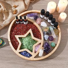 a wooden bowl filled with lots of different types of rocks and stones next to candles