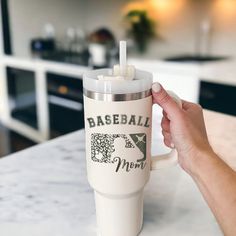 a person holding a coffee cup with a straw in it's mouth and the words baseball mom on it