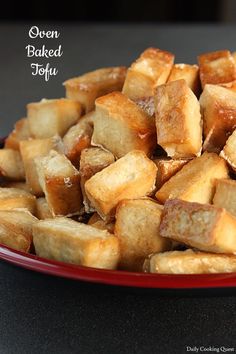 a red plate filled with ovened tofu on top of a black countertop