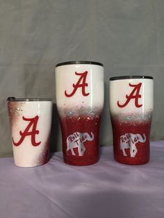 three red and white cups with the letter a painted on one side and an elephant drawn on the other